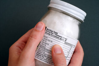 Coconut oil jar with nutrition facts in woman hands